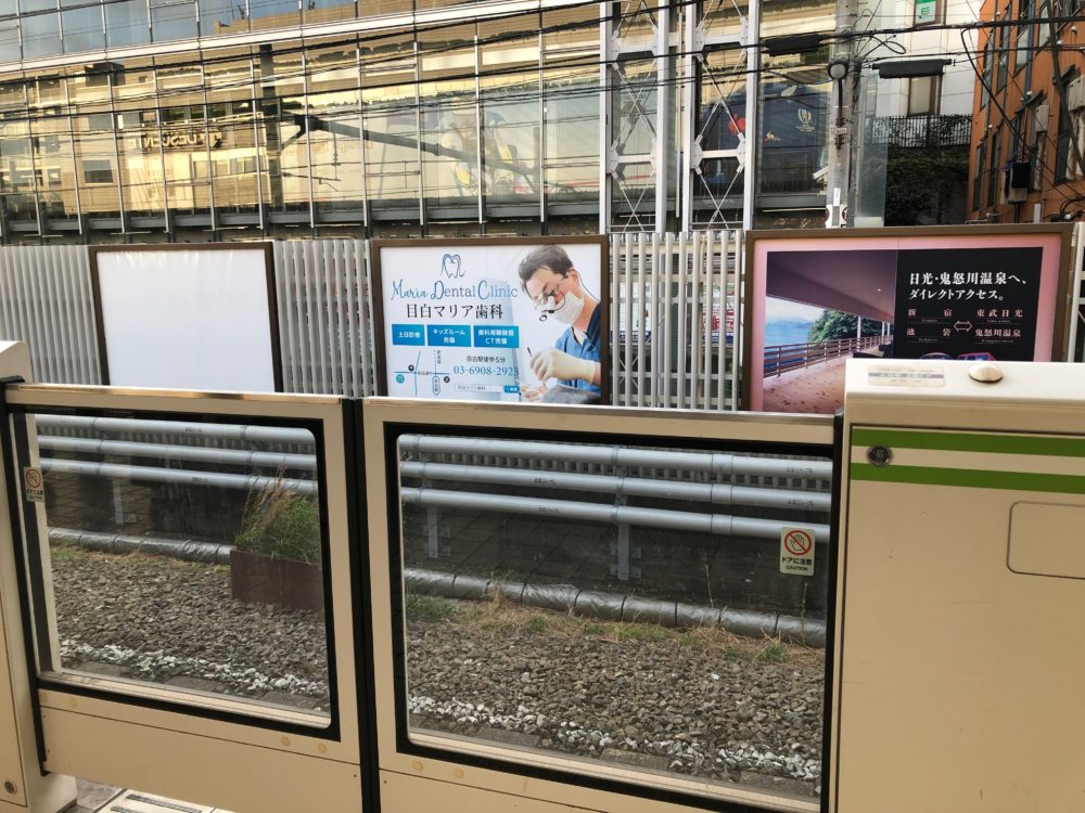 JR山手線目白駅池袋方面行ホームに設置された目白マリア歯科の看板と周りの画像